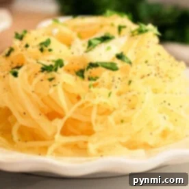 A slow cooker spaghetti squash sits on the plate, enhanced by a parsley garnish and a sprinkle of black pepper.