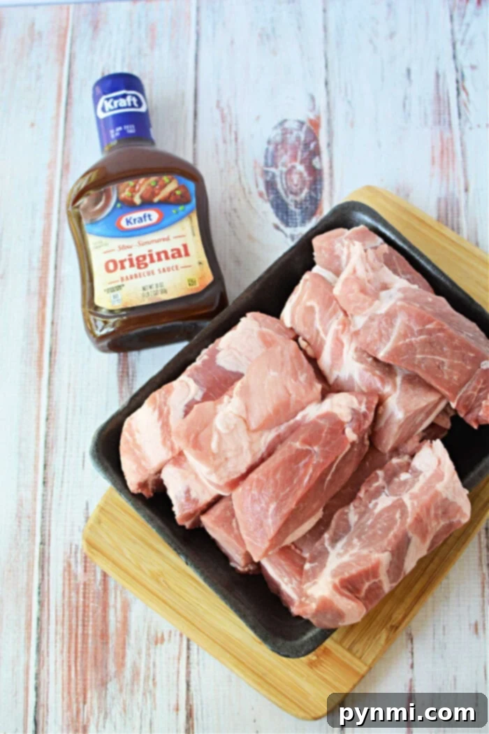 Raw boneless pork ribs rest on a black tray beside a bottle of Kraft Original Barbecue Sauce, perfect for your next pork ribs recipe, all set on a wooden surface.
