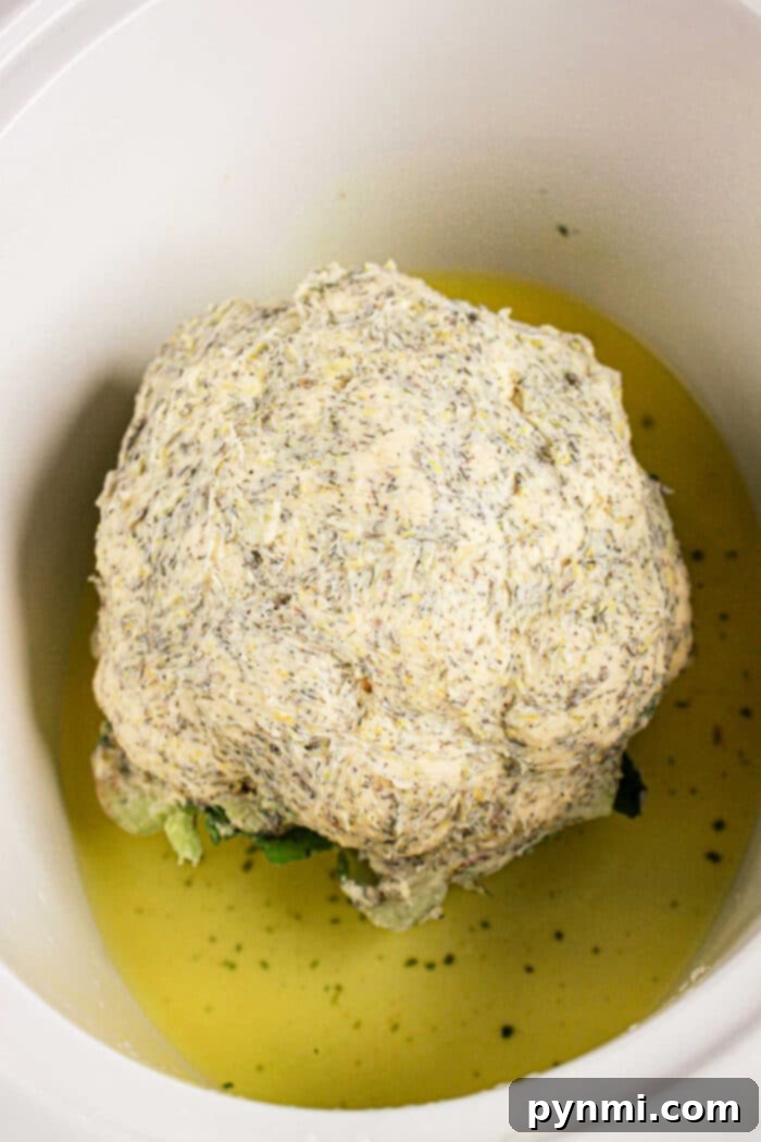 Perfectly Tender Whole Cauliflower Slow Cooker Edition 5 A whole cauliflower head rests in a crock pot, gently coated with a seasoned sauce and partially submerged in flavorful liquid.