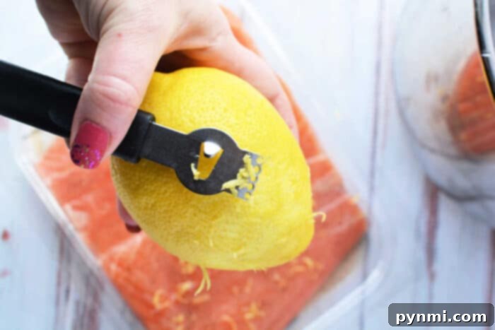 Tender Pressure Cooker Salmon in Minutes 4 A hand expertly uses a zester to zest a lemon over a fresh container of salmon, ready to be transformed into a delightful dish. Consider using your pressure cooker for perfectly tender and flavorful results in no time.