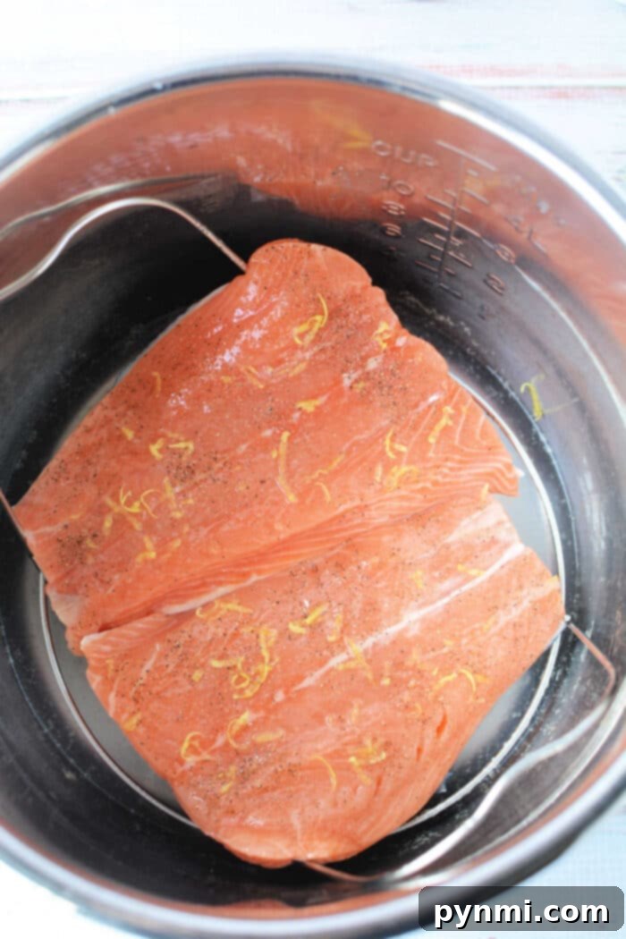 Tender Pressure Cooker Salmon in Minutes 5 Raw salmon fillets with lemon zest and pepper, nestled in a pressure cooker for a quick and flavorful meal.