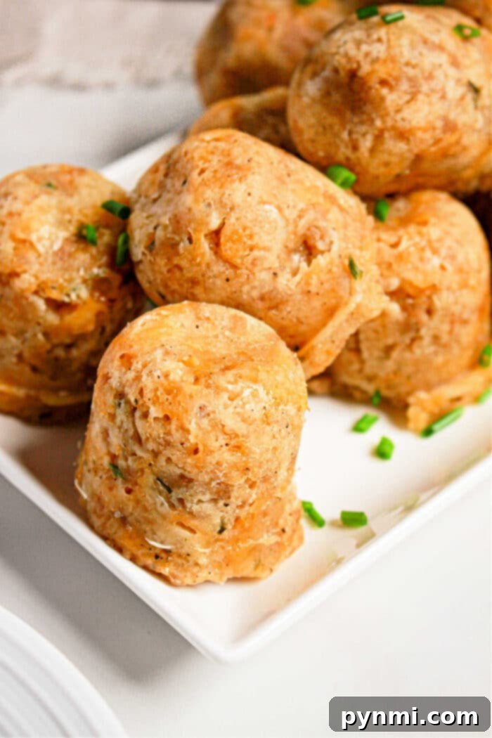 Round sausage balls made in a pressure cooker, are garnished with chopped chives on a white square plate.