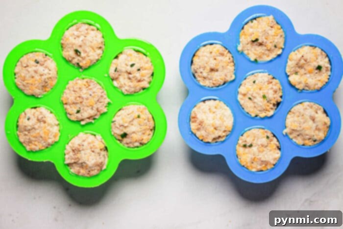 Two silicone molds filled with uncooked sausage balls, one green and one blue, sit on a light gray surface, ready to become delicious pressure cooker creations.