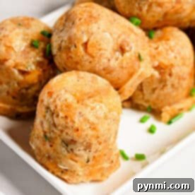 Round sausage balls made in a pressure cooker, are garnished with chopped chives on a white square plate.