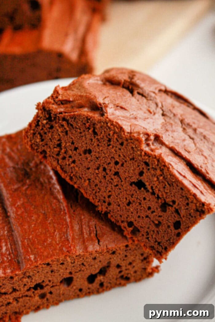 Protein-Packed Perfection Brownies 7 Close-up of two decadent slices of protein brownies on a white plate.