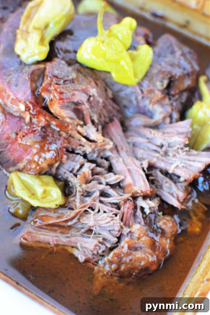 Close-up of juicy, shredded beef with peppers in rich broth, reminiscent of a savory Mississippi Pot Roast.