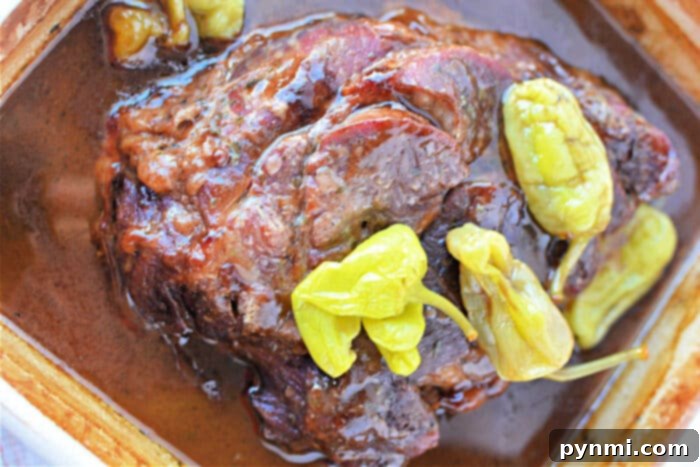 Enjoy a delightful Mississippi Pot Roast featuring juicy roast beef in brown sauce, topped with vibrant green pepperoncini peppers.