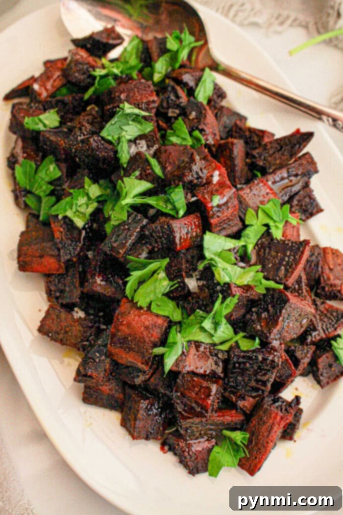 Cubed vibrant purple sweet potatoes sit elegantly on a white plate, complemented by a handy spoon.