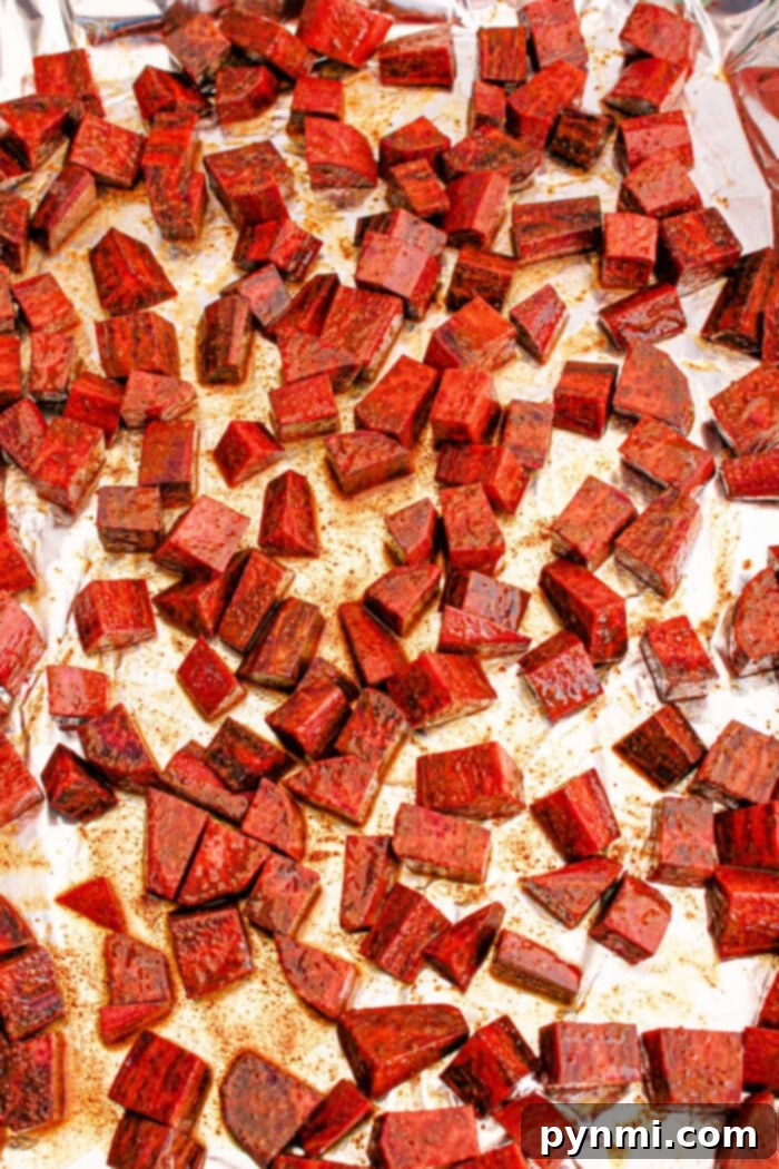 Cubed roasted purple sweet potatoes on a foil-lined baking sheet, seasoned and evenly spread.