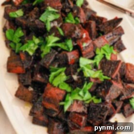 Cubed vibrant purple sweet potatoes sit elegantly on a white plate, complemented by a handy spoon.