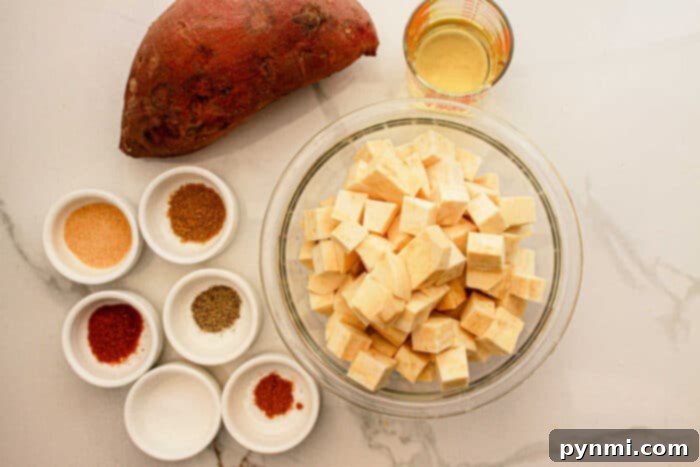 White Sweet Potato Delights 3 Cubed white sweet potatoes in a bowl, a whole white sweet potato, oil, and spices in small bowls on a white surface—perfect for your next delicious White Sweet Potato Recipe.
