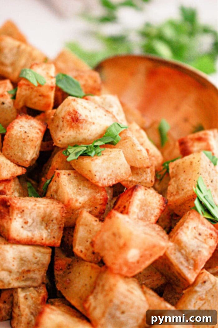 White Sweet Potato Delights 6 Crispy roasted white sweet potato cubes garnished with fresh parsley, with a wooden spoon in the background—a delicious white sweet potato recipe.