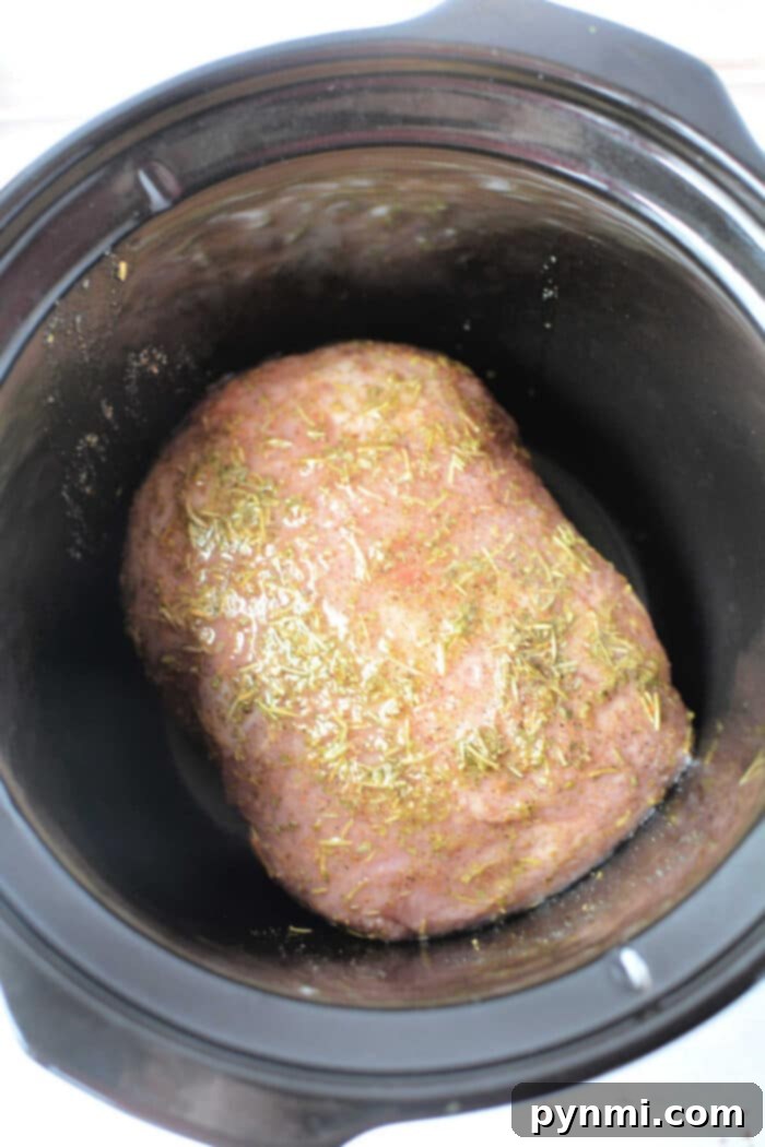Mouthwatering Slow Cooker Porketta Roast 4 A seasoned Porketta Roast rests in a sleek black slow cooker, ready for cooking.