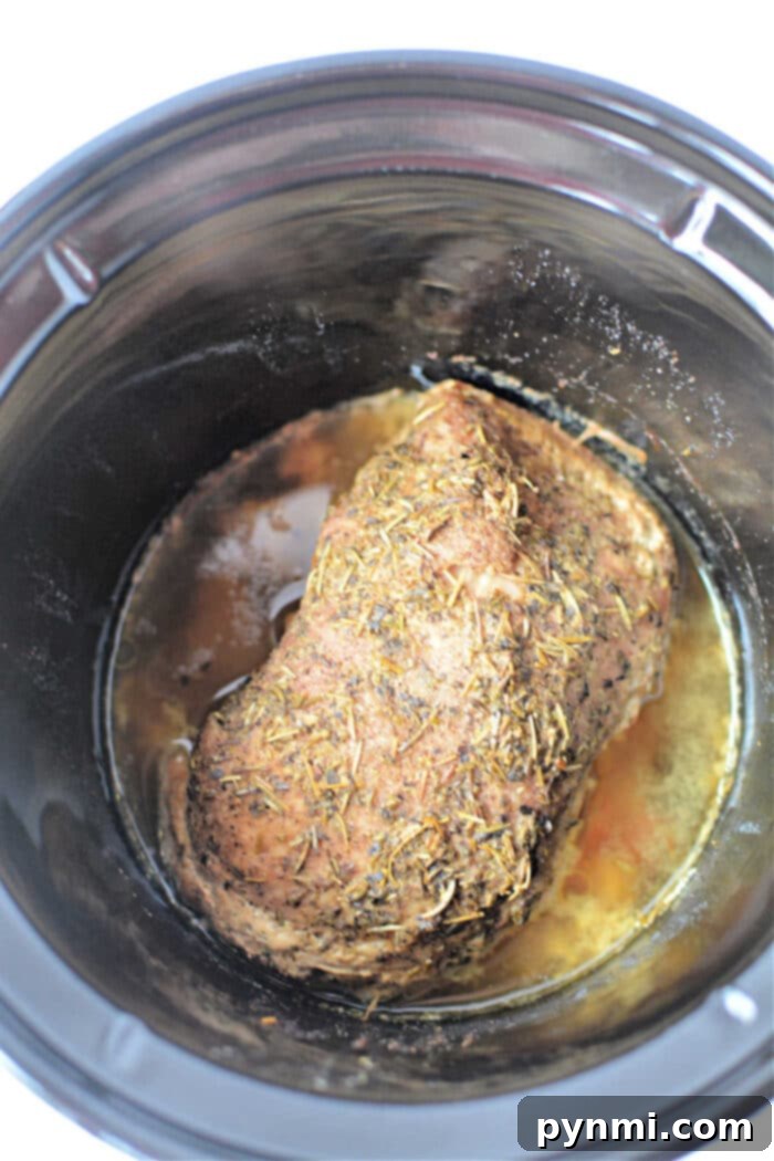 Mouthwatering Slow Cooker Porketta Roast 5 A seasoned Porketta Roast is cooking slowly, melding flavors with its rich, savory juices.