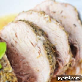 Sliced roasted porketta seasoned with herbs served on a white plate, garnished with a basil leaf.