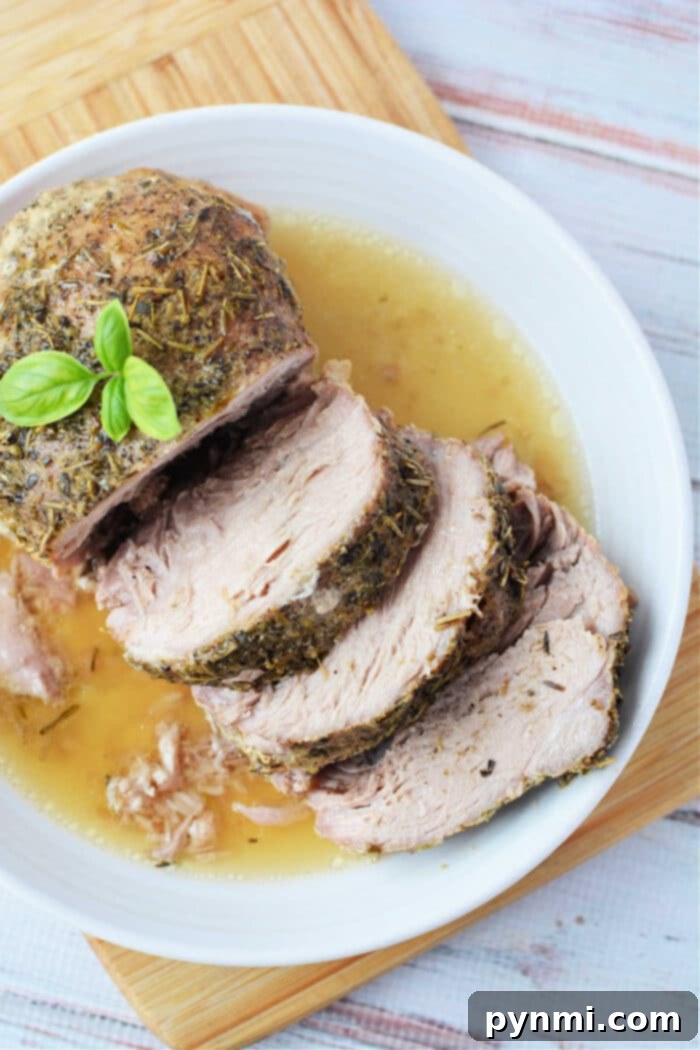 Mouthwatering Slow Cooker Porketta Roast 7 Enjoy a deliciously tender Crockpot Porketta Roast, perfectly herb-crusted and sliced, served with rich gravy on a white plate. Garnished with fresh basil for an added touch of flavor.