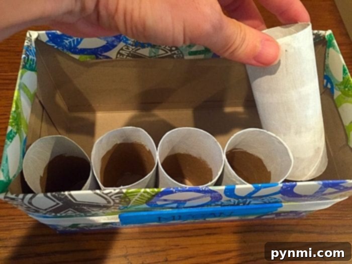 Give Kleenex Boxes a Second Life 11 An assembled desk organizer made from a repurposed Kleenex box, filled with colorful painted toilet paper rolls, holding various school supplies.