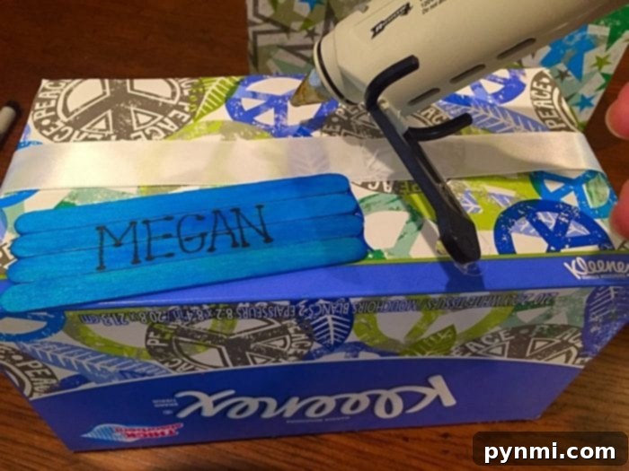 Give Kleenex Boxes a Second Life 9 A repurposed Kleenex box featuring a personalized name label made from colorful popsicle sticks, ready to organize school supplies.