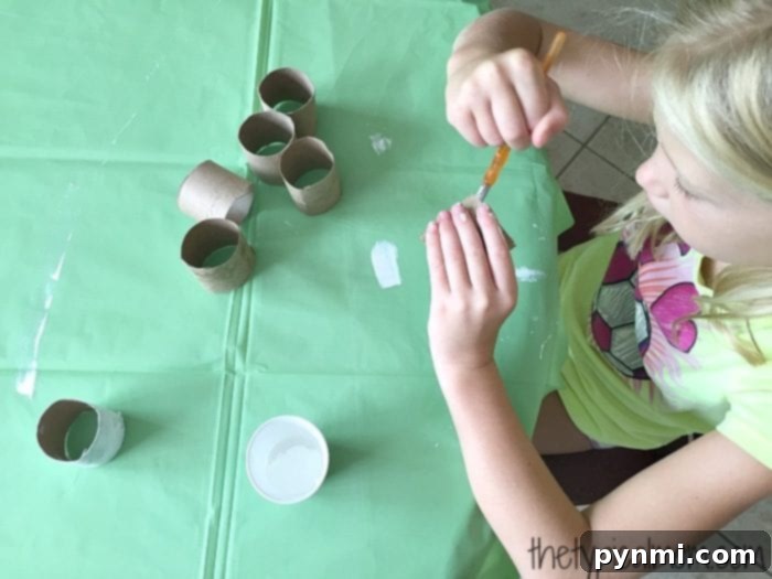 Give Kleenex Boxes a Second Life 10 Children's hands painting empty toilet paper rolls in various colors, as part of a fun repurposing activity.