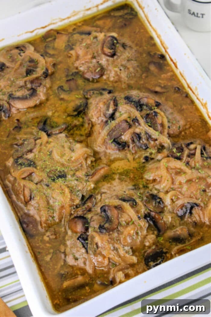 Homestyle Ground Beef Steak 2 Baked hamburger steak in gravy with mushrooms and onions, reminiscent of classic Hamburger Steak flavors, served in a white casserole dish.