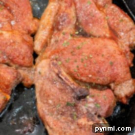 Seared flavorful Pork Shoulder Steak, coated with seasoning and sizzling in a cast iron skillet.