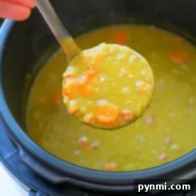 A ladle of crock pot express split pea soup with carrots and ham held over a pot.