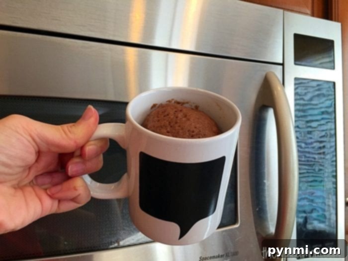 A top-down view of a freshly baked chocolate mug cake, still warm and inviting, ready to be frosted.