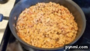 Cooked seasoned ground meat in a black skillet on a stovetop, perfect for adding rich flavor to your favorite crockpot tortellini soup recipe.