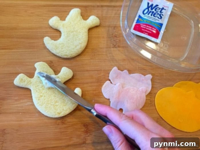 Halloween-themed deconstructed school lunch featuring ghost-shaped bread and bat-shaped deli meat, ready for kids to assemble.