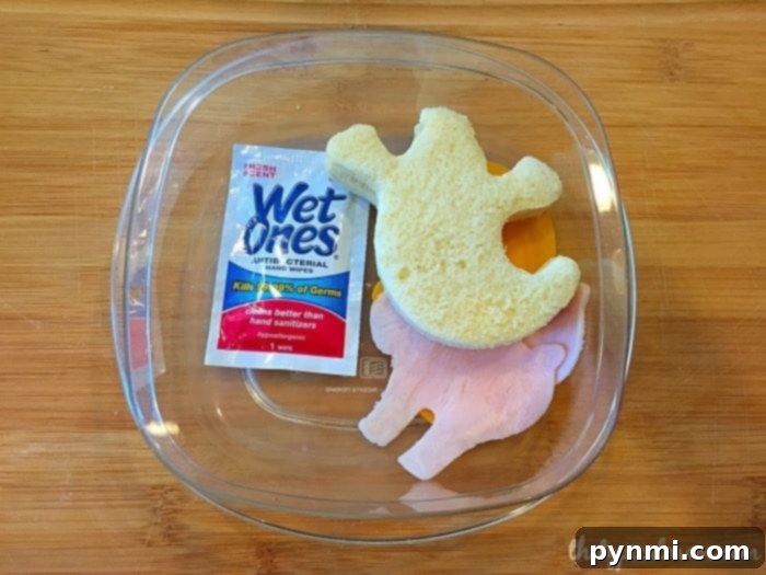 Close-up of a deconstructed sandwich preparation, showing meat and cheese cut with cookie cutters and bread prepped with a thin layer of mayo.