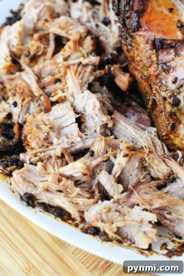 Shredded, seasoned pork roast on a white plate atop a wooden surface—perfect for showing off your favorite oven pork roast recipe.