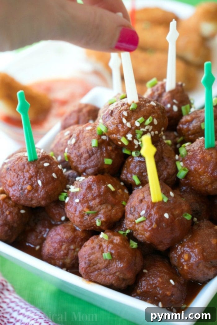 A hand picking a saucy barbecue meatball with a skewer from a bowl garnished with sesame seeds and chives, fresh from the Instant Pot, ideal for a football party.