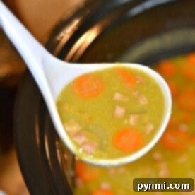 A ladle of slow cooker split pea soup with ham and carrots overflows the crockpot.