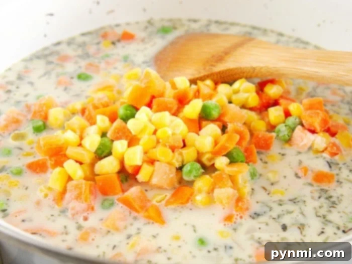Simple chicken pot pie filling recipe, being stirred with a wooden spoon.