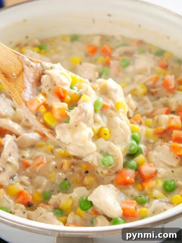 A spoonful of creamy simple chicken pot pie recipe, brimming with peas, corn, and carrots.