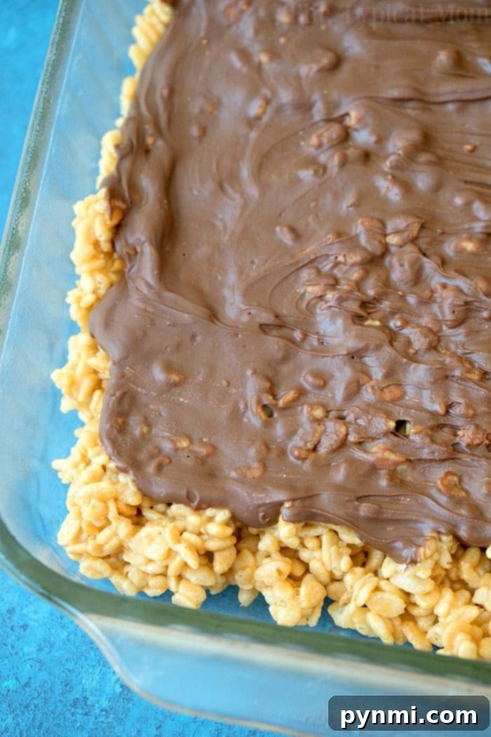 No-bake Scotcheroos recipe base made with Rice Krispies or Cheerios, ooey gooey and addictive. A large pan filled with the cereal base for Scotcheroos, ready for the topping