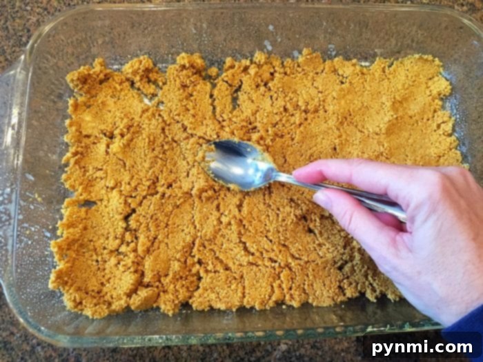 Cookie bar base with graham cracker crumbs pressed into a pan.