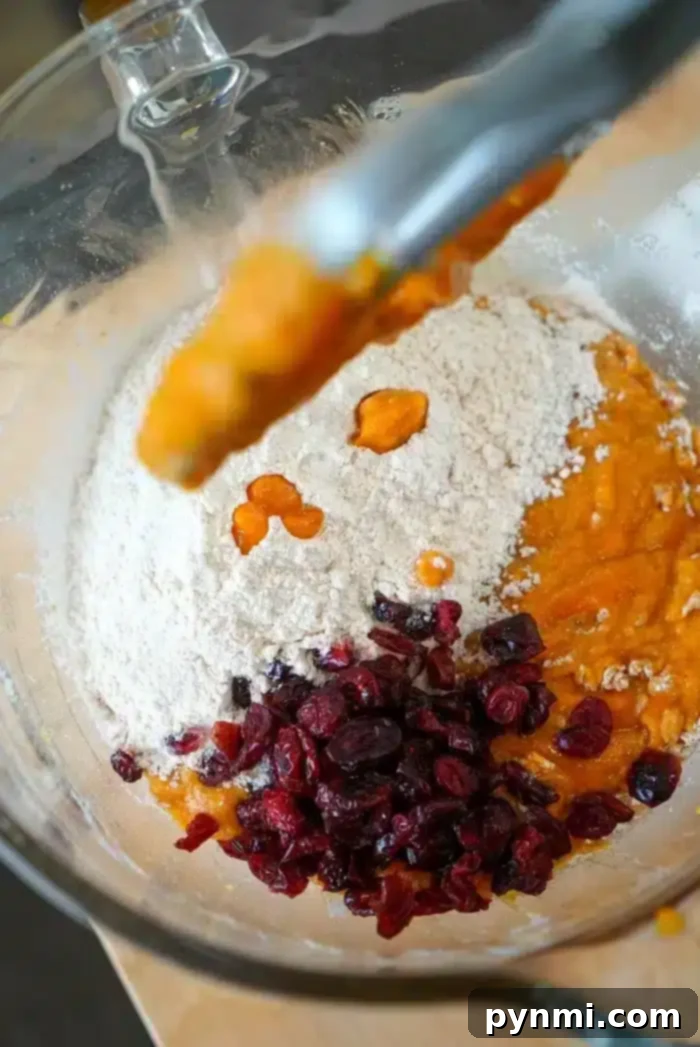 Tender Spiced Pumpkin Loaf 3 Mixing bowl with flour, cranberries, and rich pumpkin puree—perfect for crafting moist pumpkin bread delights.