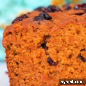 Tender Spiced Pumpkin Loaf 4 Close-up of a slice of easy pumpkin bread, against a colorful background.