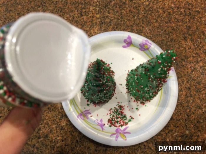Sugar cone dipped in green chocolate with colorful sprinkles, ready to become a Christmas tree cupcake topper.