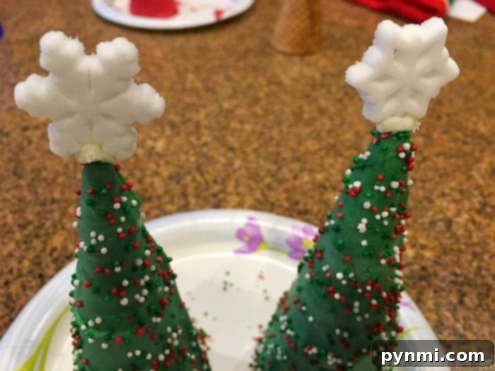 Two decorated sugar cone Christmas tree toppers sitting on a plate, showcasing festive ornament sprinkles.