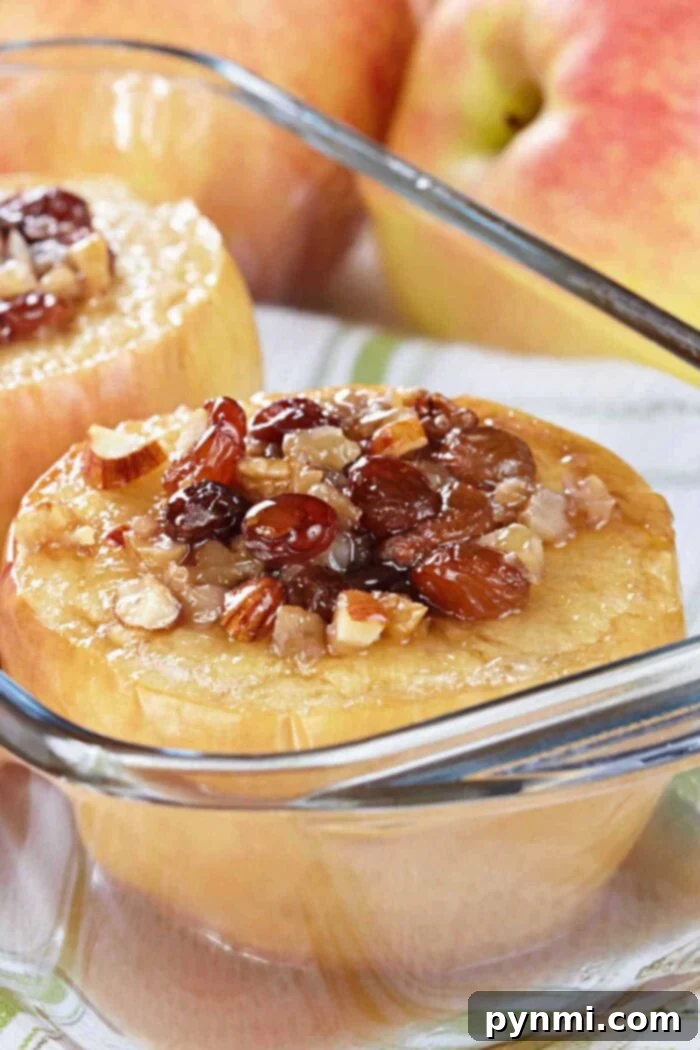Beautifully baked whole apples, stuffed with a golden-brown oat and caramel mixture, presented in a dish with fresh apples in the background, showcasing an easy method to bake whole apples.