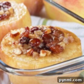 Baked apples filled with nuts and raisins in a glass dish, with fresh apples in the background, provide a delightful guide on how to bake whole apples.
