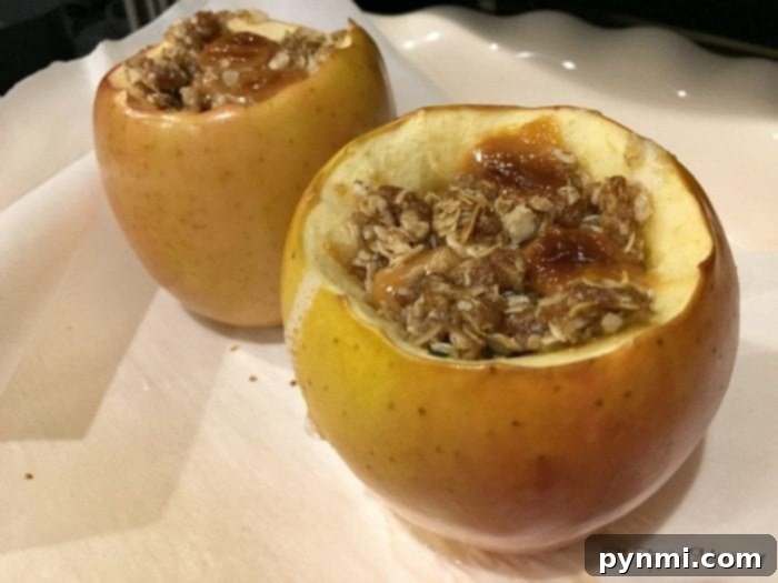 A baked apple cut in half, revealing the gooey caramel and oat filling, highlighting an easy baked apple recipe.