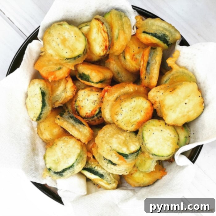 A perfect recipe for crispy fried zucchini chips. A close-up of a bowl filled with freshly fried zucchini chips, showing their crispy texture and golden-brown color.
