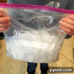 A person holds a clear plastic bag with a Hefty logo, its contents resembling ingredients for how to make ice cream at home, ready to transform into a delightful dessert.