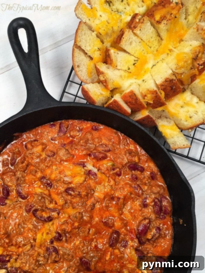 Cheesy chili dip recipe with garlic pull apart bread....the best appetizer ever!! Delicious cheesy chili dip served warm in a cast iron skillet, ready to be enjoyed with bread.