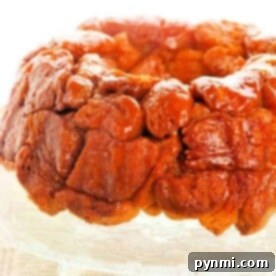 Monkey bread with a glossy caramelized glaze sits enticingly on a decorative glass plate, showcasing the allure of an easy monkey bread recipe.