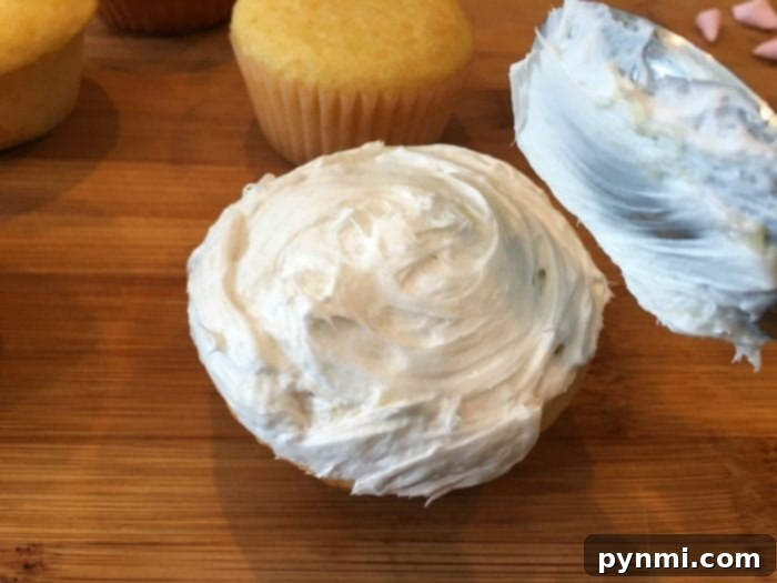 Close-up of a cupcake being decorated with sliced mini marshmallows for a sheep's fluffy wool.