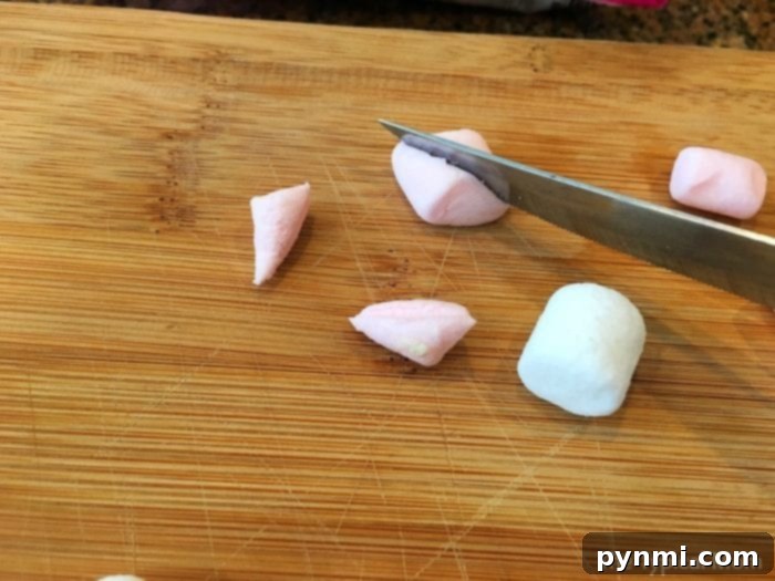 Step-by-step image showing how to add mini marshmallows to create the sheep's wool on an Easter cupcake.